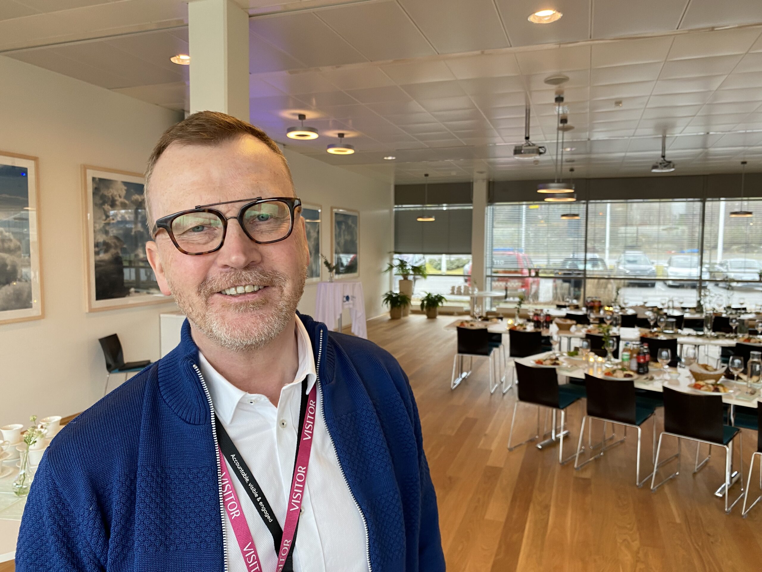 Nærbilde av mann med TCMs festlokaler i bakgrunnen. Foto